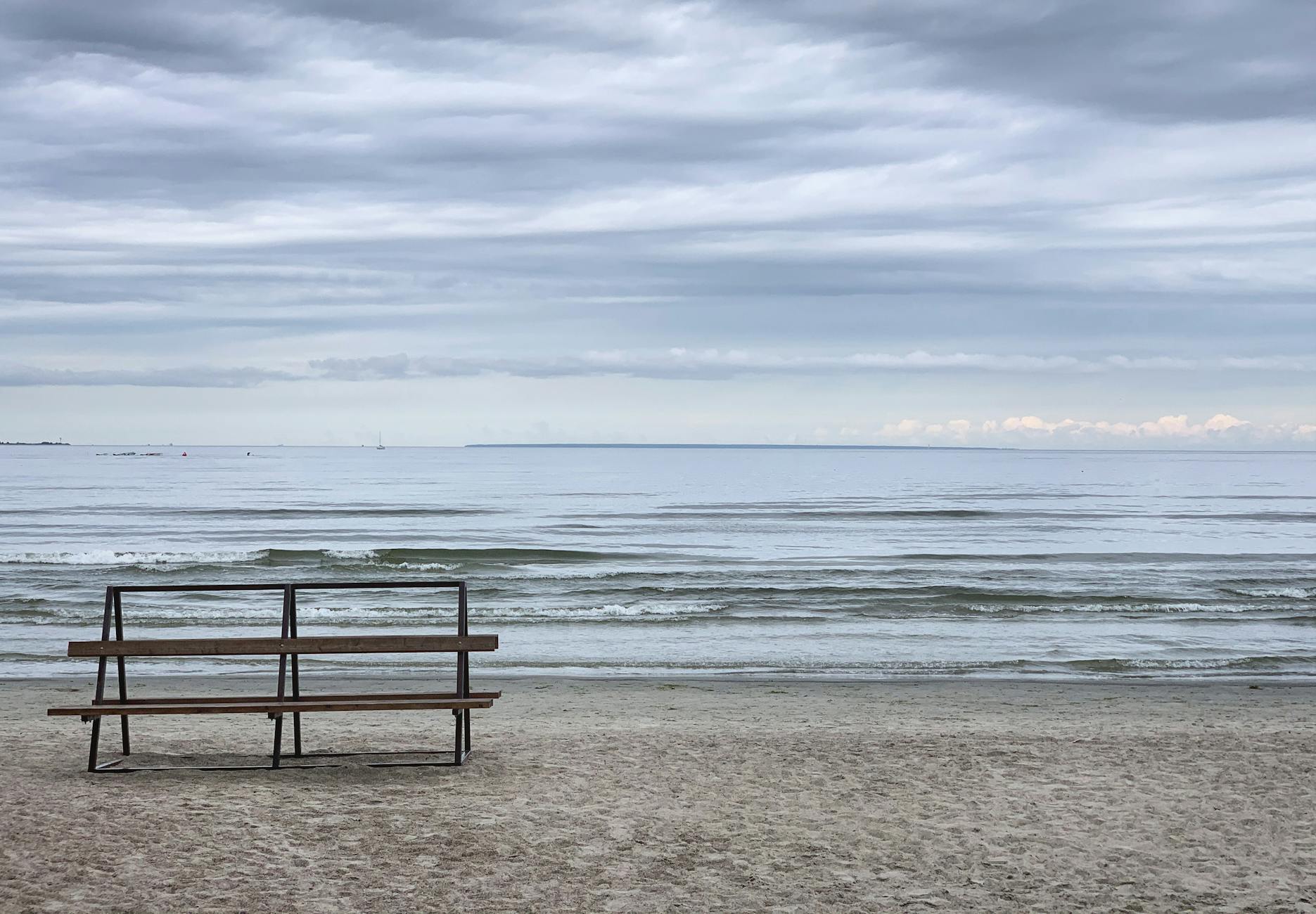 Serene view of an empty bench facing the Baltic Sea under a cloudy sky in Tallinn, Estonia.