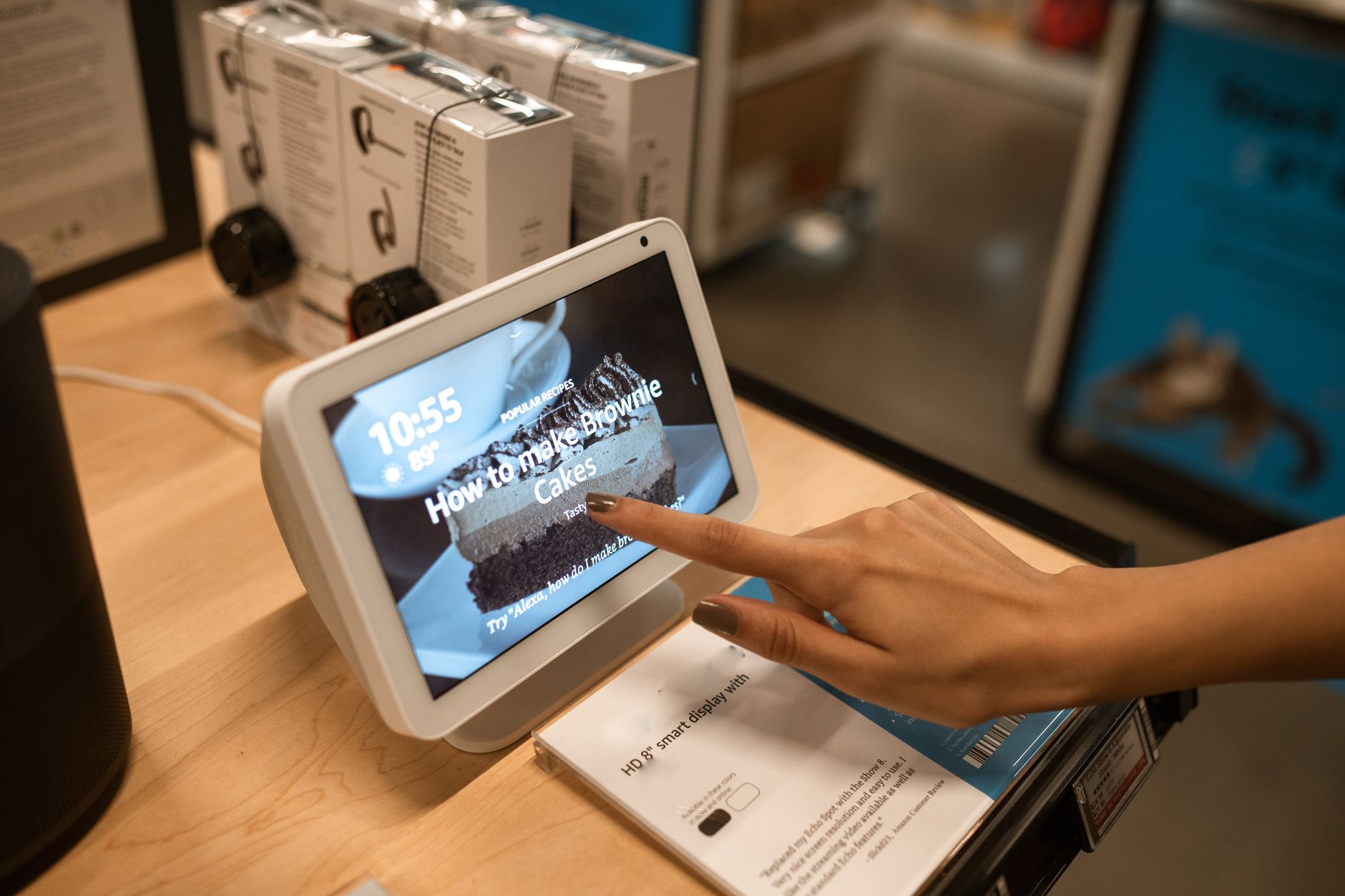 Close-up of a hand using a smart display showing a recipe for brownie cakes in a store setting.