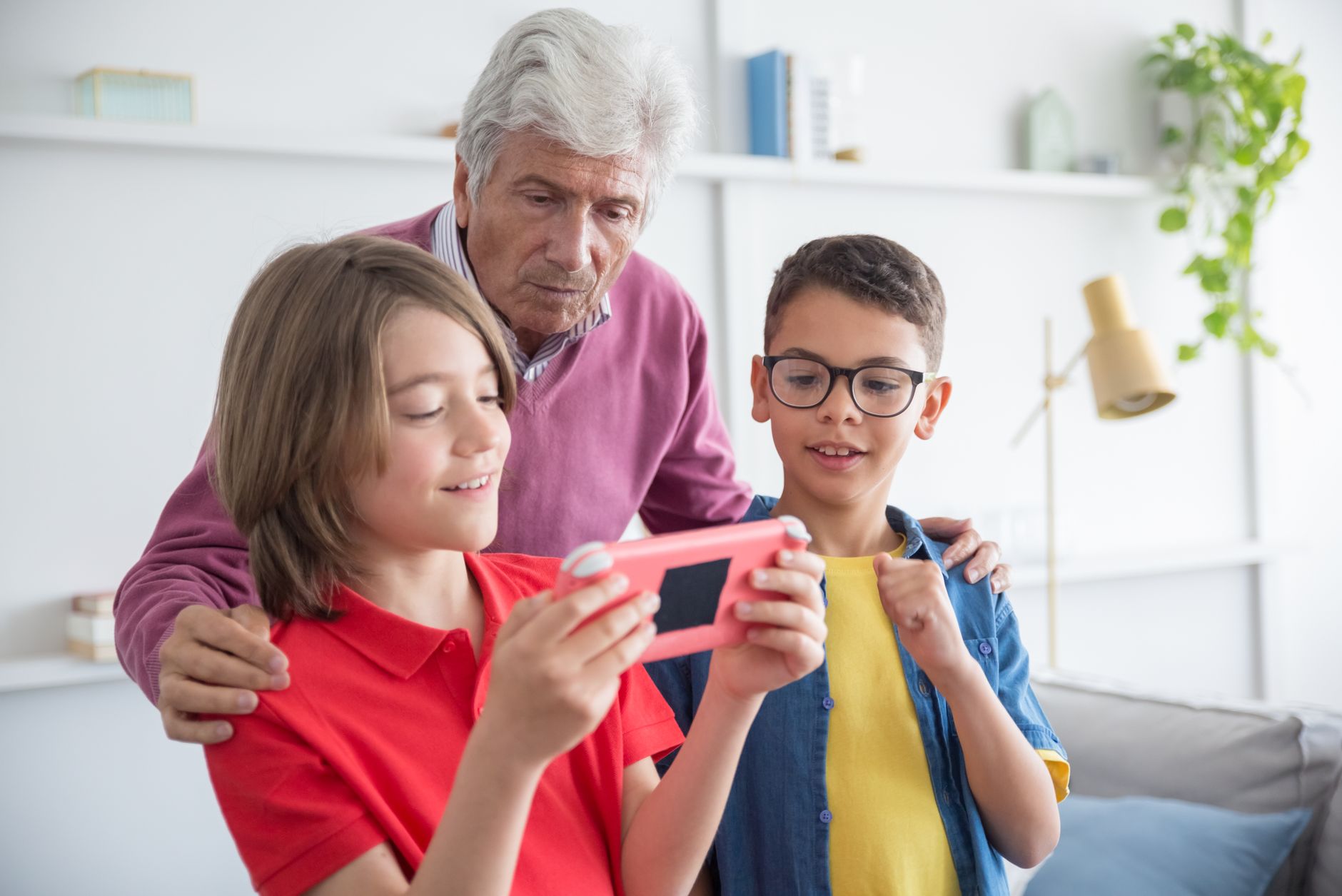 Grandfather and grandchildren bonding while playing a video game at home.