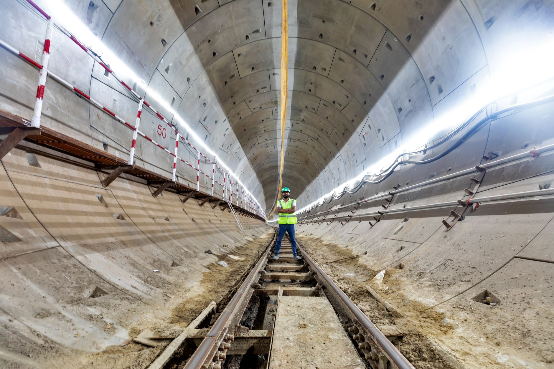 Engineer in safety gear inspects a subway tunnel under construction, highlighting urban development.
