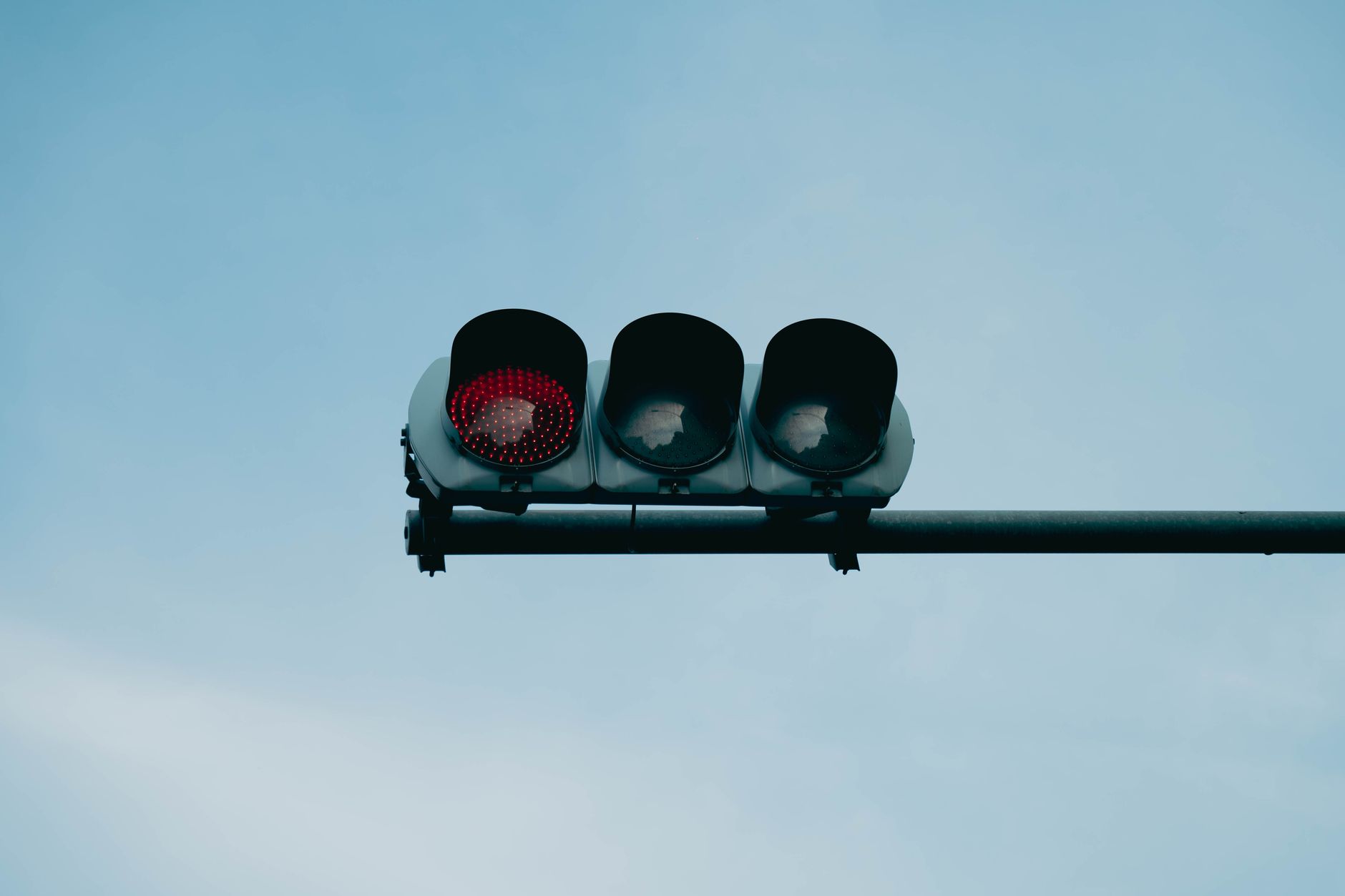 A close-up of a red traffic light set against a clear blue sky, conveying safety and caution.