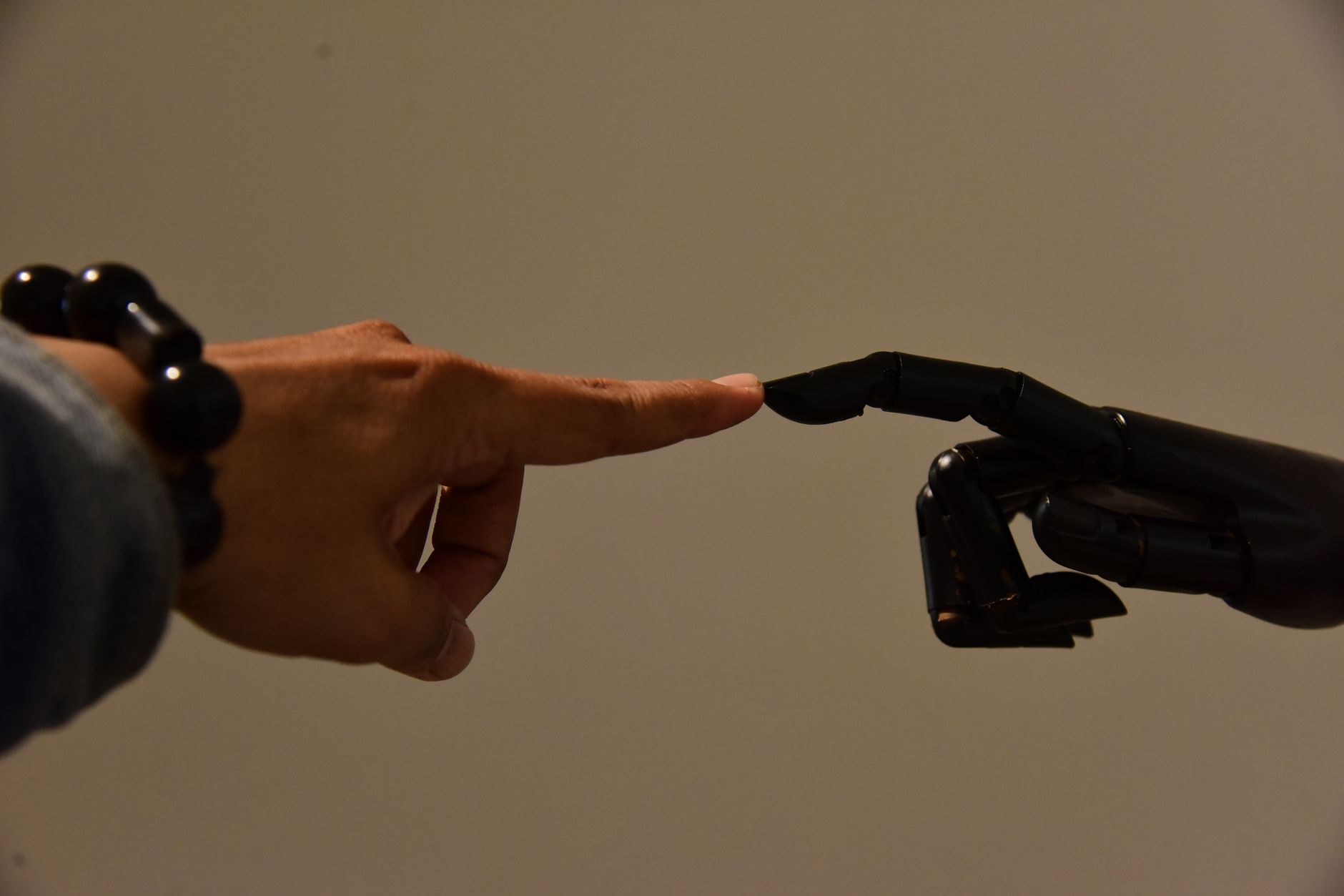 A human hand and a robotic hand extending fingers to touch, symbolizing connection.