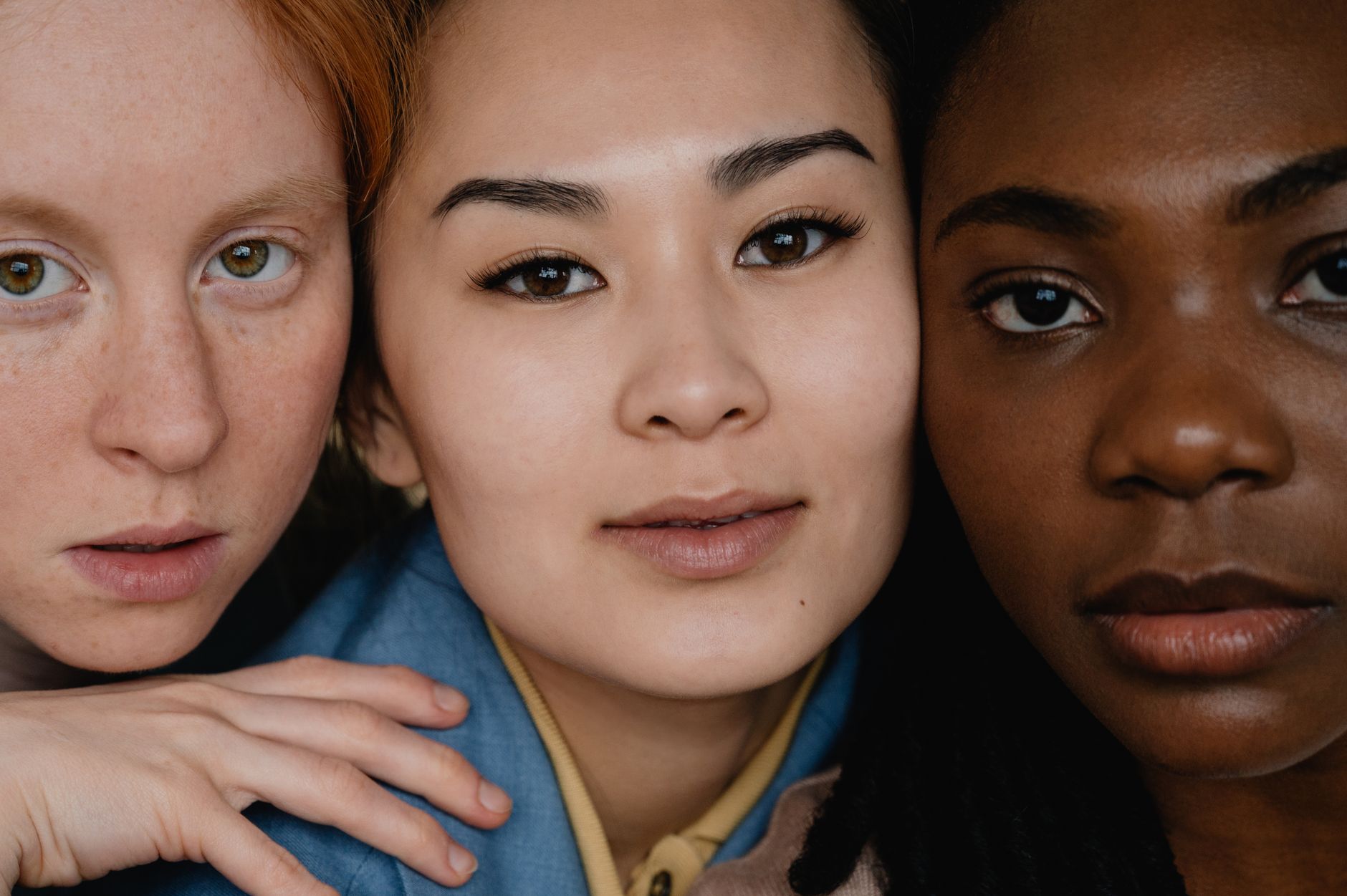 Close-up portrait of three diverse women showcasing natural beauty and diversity.