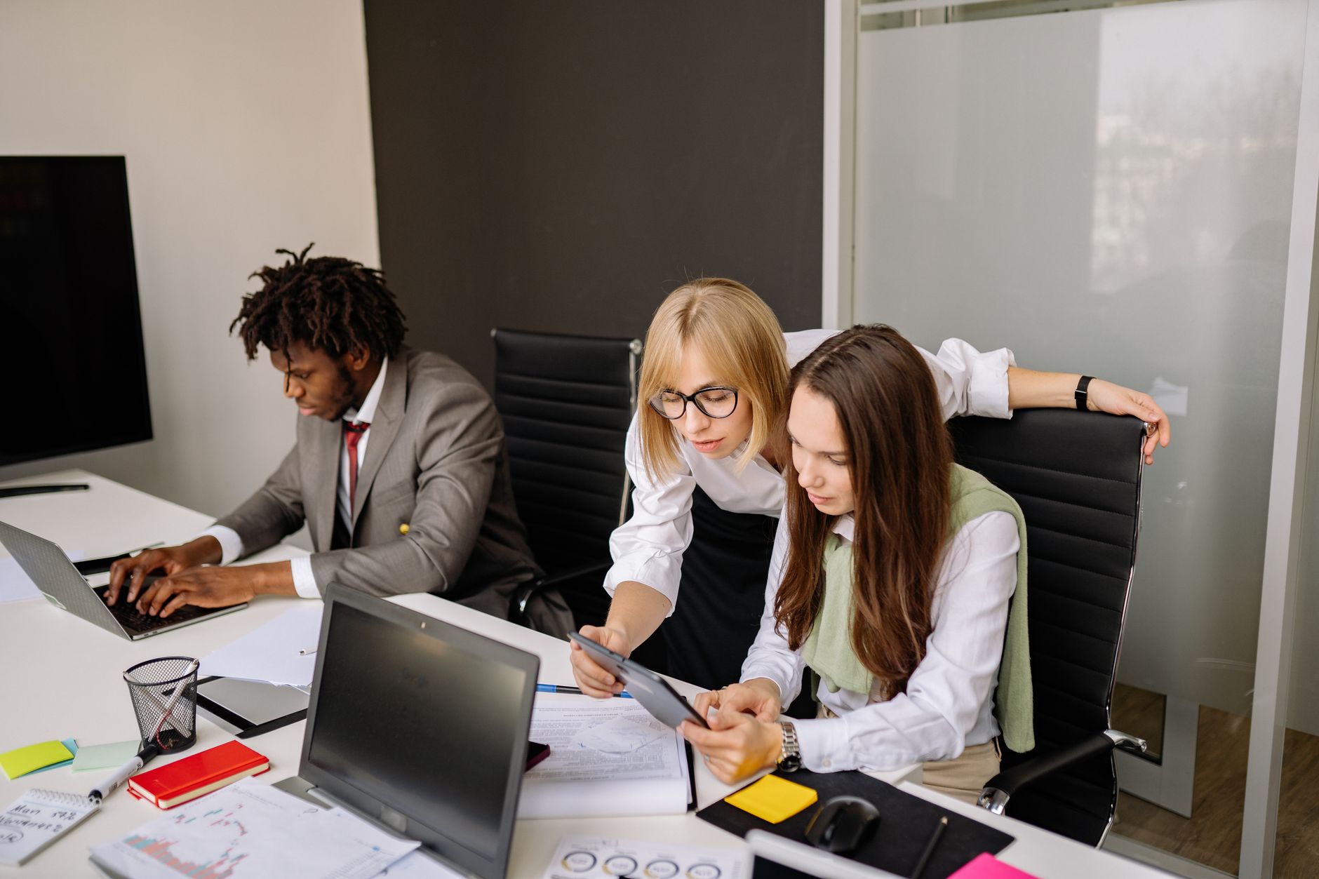 Business team collaborating in a modern office setting with laptops and tablets.