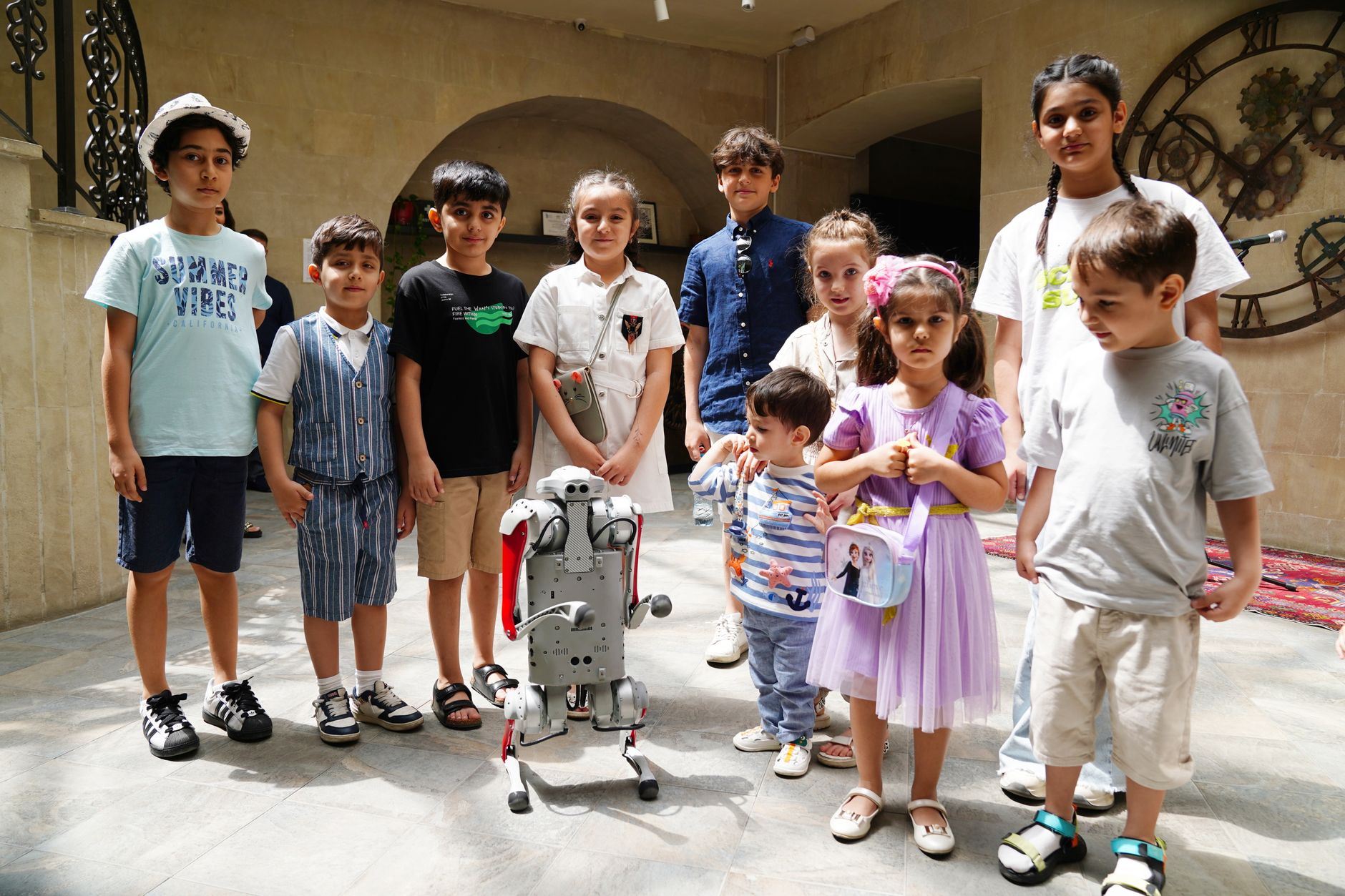A diverse group of children joyfully interacting with a humanoid robot indoors, showcasing future technology.