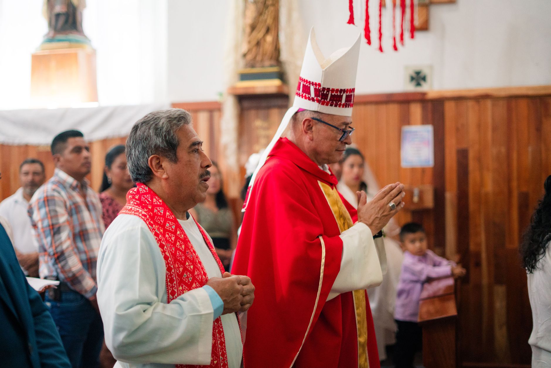 Catholic priest in traditional vestments during a religious ceremony in a church setting.