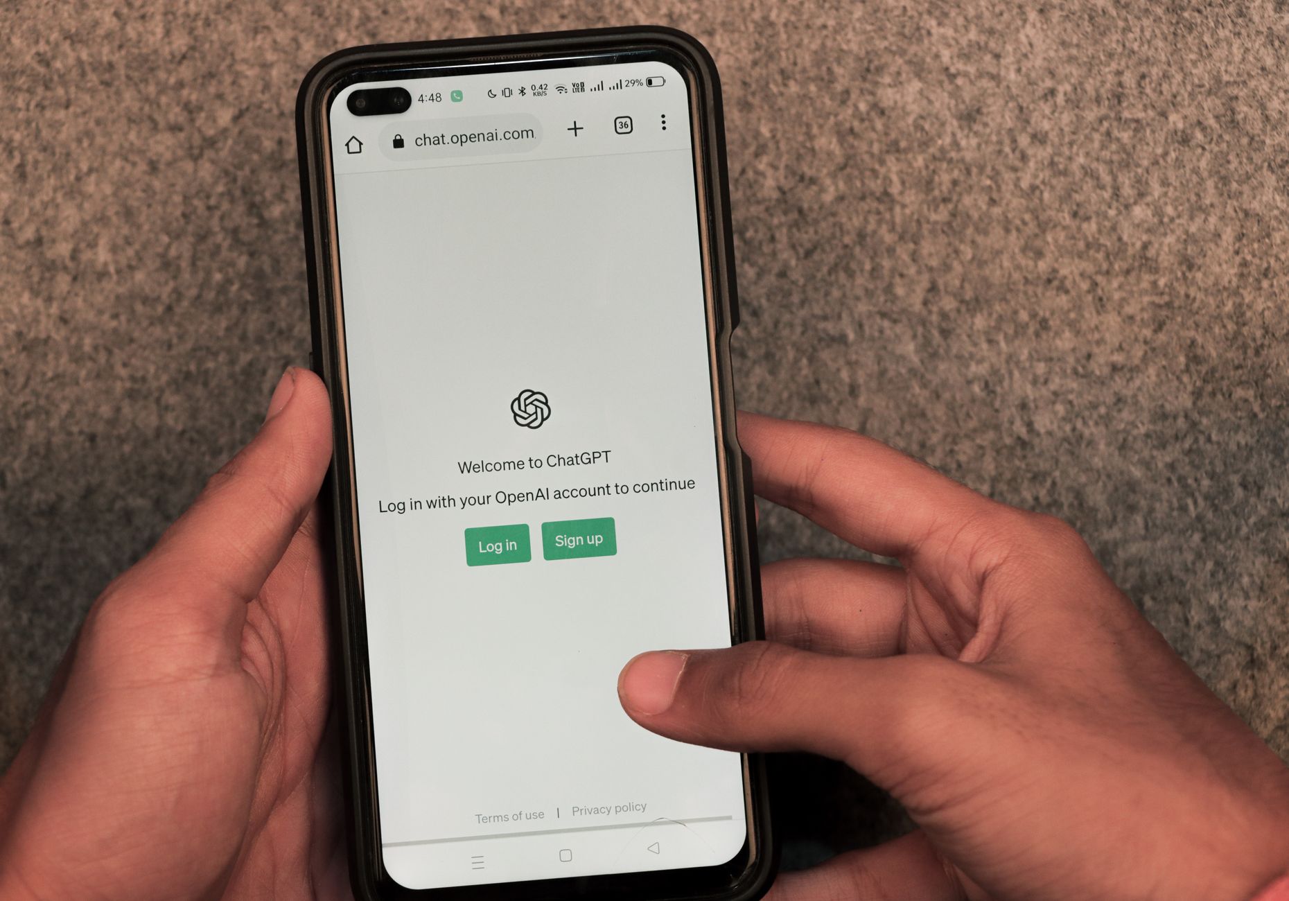 Close-up of hands using smartphone with ChatGPT app open on screen.