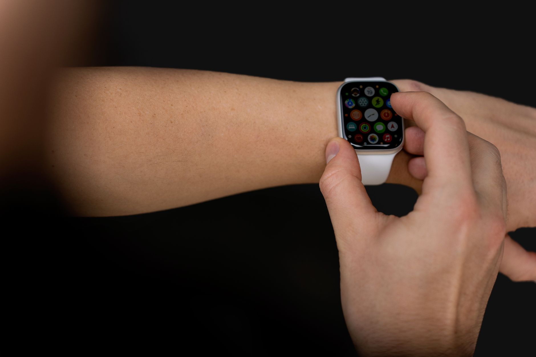 A person interacts with a touchscreen smartwatch against a black background, showcasing modern technology.