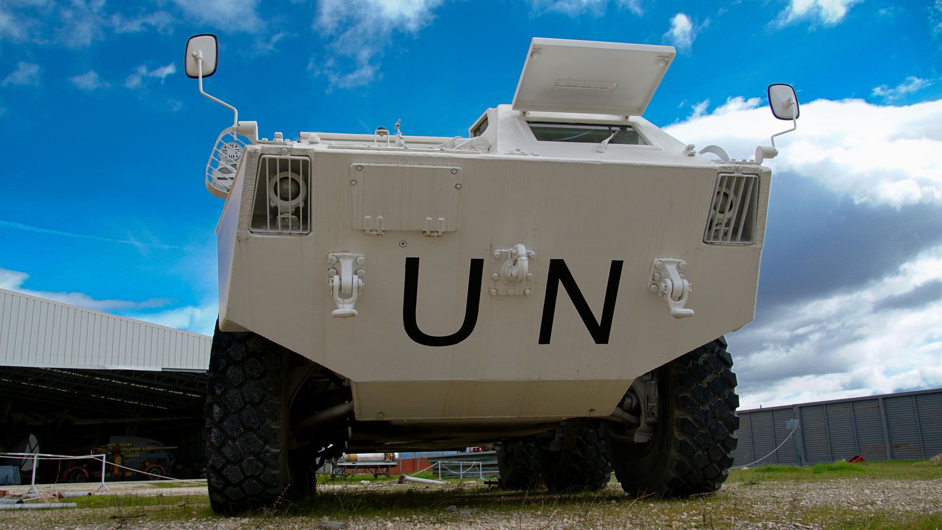 Low-angle view of a UN armored vehicle in Madrid, with clear blue sky and industrial background.