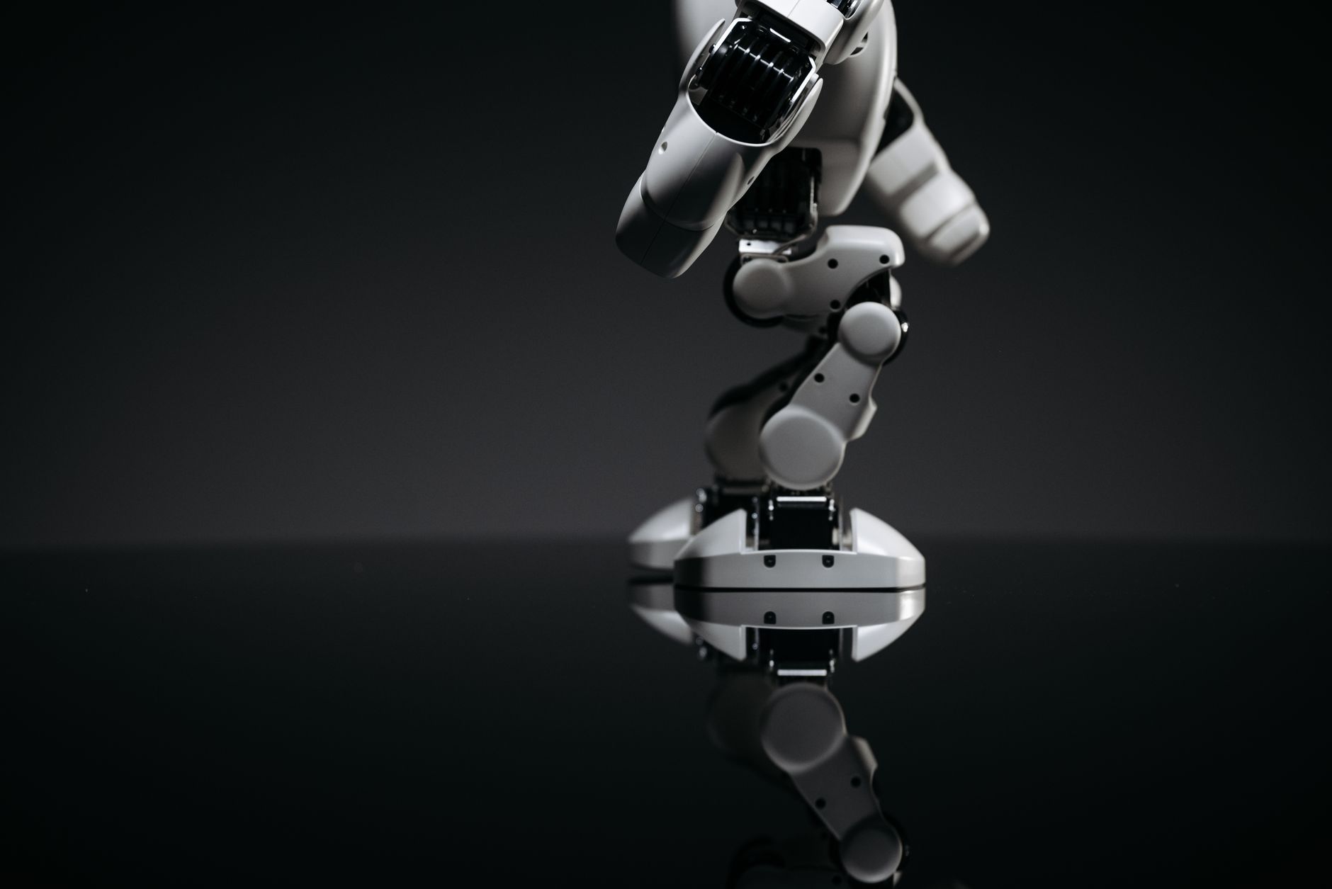 A close-up image of a mechanical robotic arm reflecting on a dark surface, capturing industrial innovation.