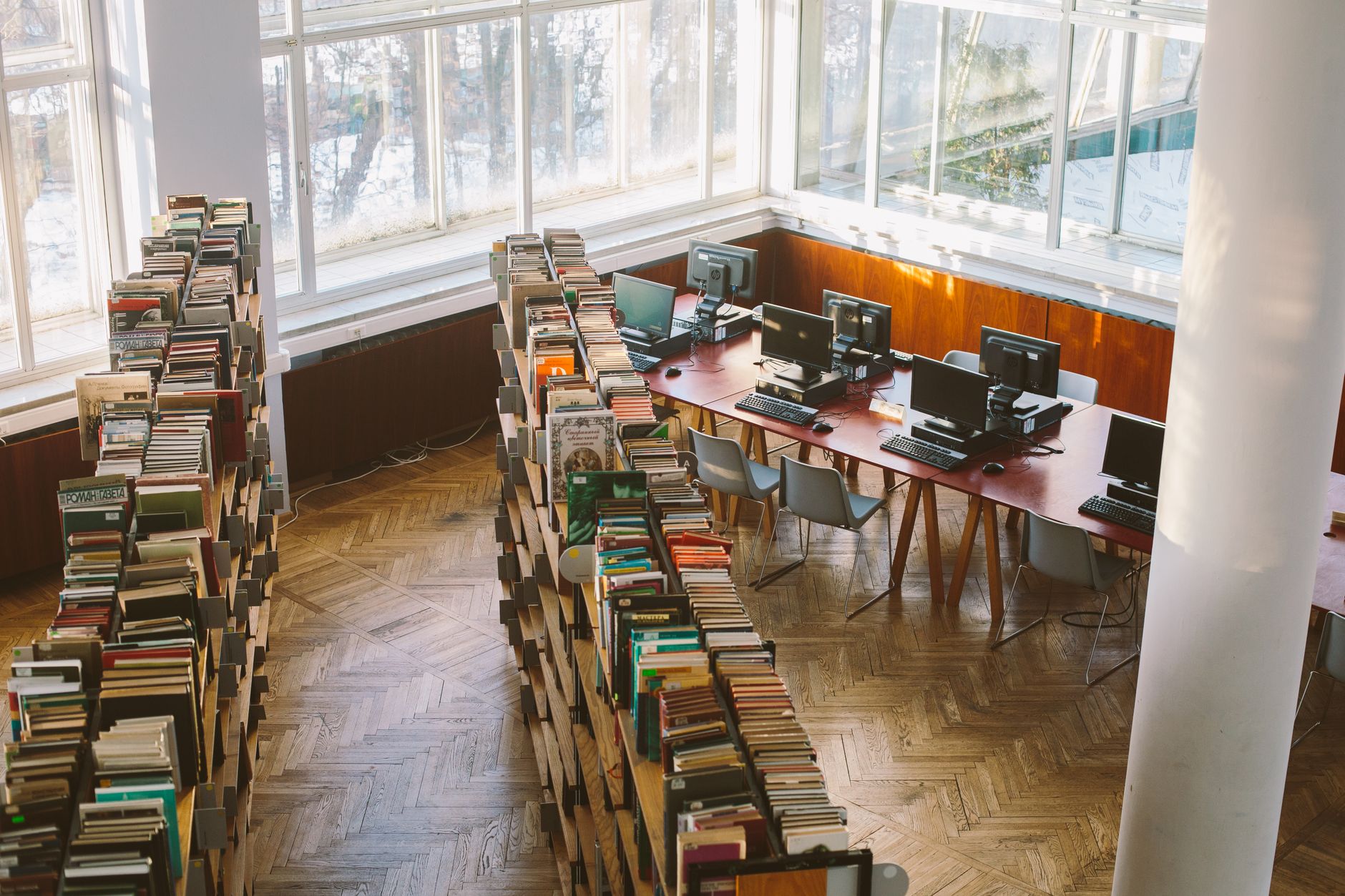 A university library viewed from above, featuring bookshelves and computer stations under natural daylight.